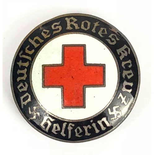 German Third Reich Red Cross Lady Helper badge.  Good scarce lightly dished circular example in enamels. Black border with Deutches Rotes Kreuz Helferin and swastikas, central white field bearing Red Geneva Cross. Reverse bears Ges.gesch. Complete with pin and hook. Small chip to border above Rotes. GC