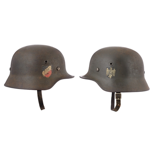 German Third Reich Army Double Decal Steel Helmet.  A scarce rolled edge example with Army eagle to the left side (90% present) and National shield to the right (70%). Retaining original green painted finish to the shell. The interior with alloy band supporting leather lining and chinstrap (Fragile to part) . The interior of the shell stamped with the number 1040 and E702. Some service and age wear GC.