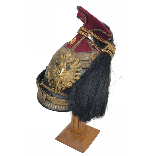 Austrian landwehrulanen (Lancer) Regiment 5 Officer's Chapka.  A rare example, with glazed black leather skull and peak, the latter edged with gold embroidery.  Two rows of gold "Austrian" pattern lace at top of skull, covering the join with the purple cloth which forms a small square top edged along the corners with gold "Heavy Russia" braid.  A large ornate brass front plate in the form of a Crown above a double-headed eagle bearing a shield on the breast incised with numeral 5.  The black horsehair plume connected to the top of the cap by a narrow chain.  Ornate brass (originally gilt) chin-scales secured by lion's head bosses.  Pale roan leather internal headband and pleated cream silk lining.  The square top requires strengthening, remains attached.