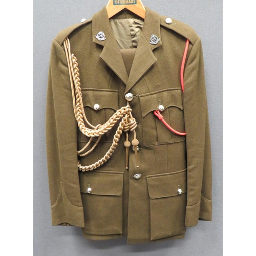 Post 1952 Royal Military Police Uniform
khaki, single breasted, open collar tunic.  Pleated chest pockets and lower bag pockets, all with buttoned flaps.  Silvered, QC Royal Military Police collar badges.  Anodised buttons.  Red lanyard and gilt cord aiguillette.  Together with matching trousers. 