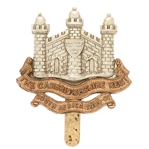 Badge. Cambridgeshire Regiment cap badge on South Africa scroll.  Good rare die-stamped white metal Castle of Cambridge, central tower bears Arms of Ely, resting on brass scrolls THE CAMBRIDGESHIRE REGIMENT over SOUTH AFRICA 1900-01.    Crimped slider.  VGC