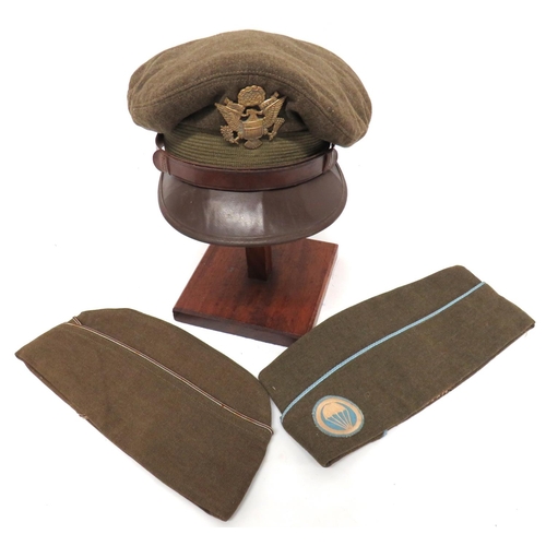 Three WW2 American Caps
consisting service dress cap with woollen khaki crown and body.  Green mohair band.  Brown leather peak and chinstrap.  Brass US eagle badge.  Leatherette sweatband ... 2 x Garrison caps.  Khaki crown and body.  One with light blue piping and embroidery parachute badge.  The other with black and gilt piping.  3 items.