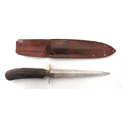 Commercial Fairbairn-Sykes Fighting Knife
6 1/2 inch, double edged blade.  Oval, brass crossguard.  Polished antler grip.  Top, brass securing disc.  Contained in its commercial leather scabbard.  The rear marked "14636505 Charkin".  Some wear to scabbard.  
