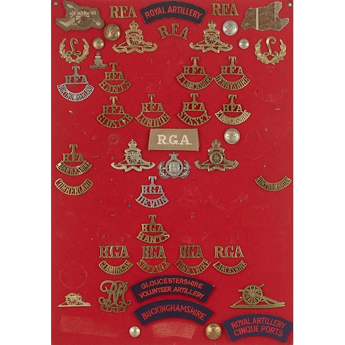 295 - Royal Artillery badges and shoulder titles.  Board with good display of approx. 48 metal and cloth i... 