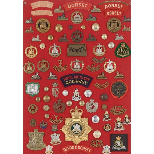 297 - Dorset military badges, shoulder titles etc.  Board with good display of approx. 83 metal and cloth ... 