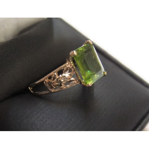 72 - 9ct yellow gold imported ring with a large Peridot stone with small diamonds to shoulders

Approx 1.... 