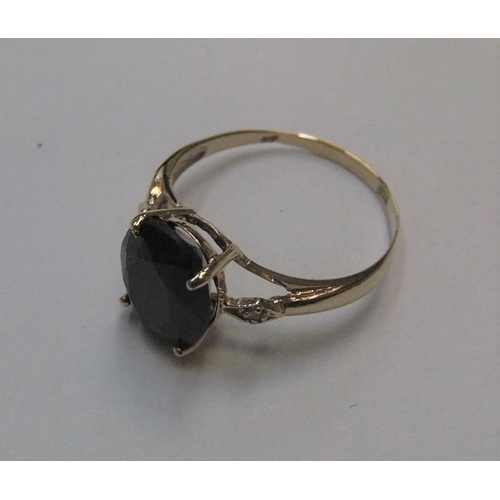 73 - 9ct yellow imported yellow gold ring set with a large black sapphire & with a small diamond set to e... 