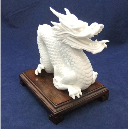 168 - Finely detailed, white fired ceramic dragon (unmarked) on chinese wood plinth,

21 cm long