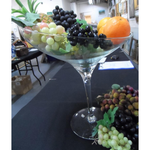 101 - Oversized, stylist wine glass, approx 50cm tall with a huge amount of plastic fruit (Qty)