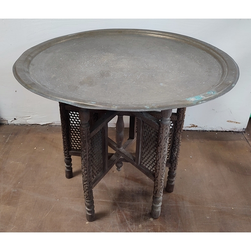 541 - Brass engraved top Moorish table with ornate wooden base

71cm diameter