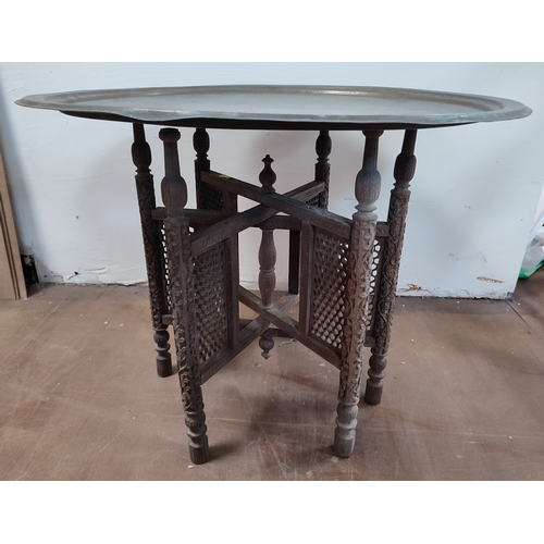 541 - Brass engraved top Moorish table with ornate wooden base

71cm diameter