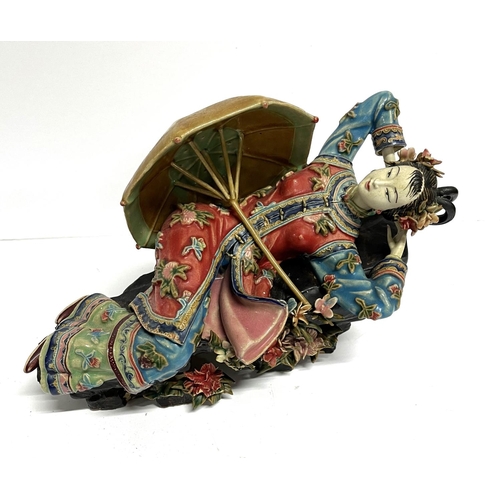 18 - Finely made Oriental ceramic figurine, depicting a reclining lady with a parasol, extensively