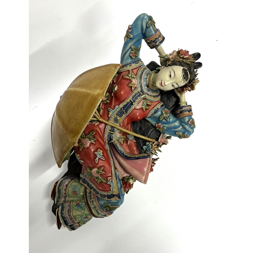 18 - Finely made Oriental ceramic figurine, depicting a reclining lady with a parasol, extensively