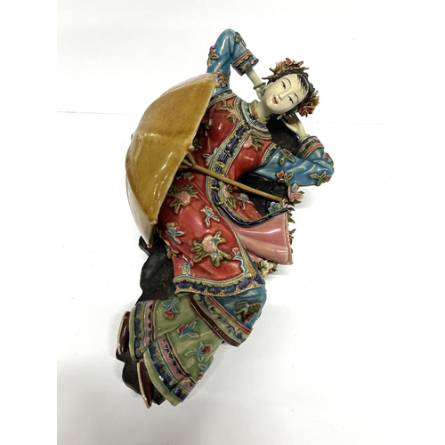 18 - Finely made Oriental ceramic figurine, depicting a reclining lady with a parasol, extensively