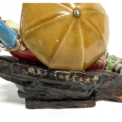 18 - Finely made Oriental ceramic figurine, depicting a reclining lady with a parasol, extensively