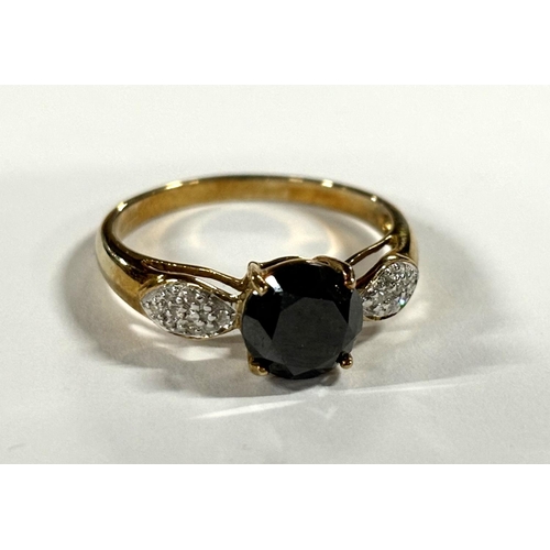 67 - 9ct yellow gold ring with central round cut black stone with Diamond chips to both shoulders