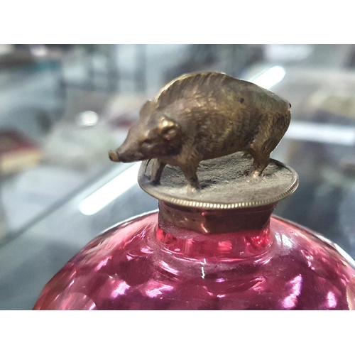 493 - Antique Cranberry glass perfume bottle with an unmarked white metal (possibly silver) wild boar cap