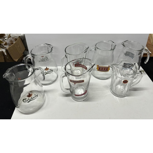 521 - 7 Glass jugs with alcohol signs on the side including San Miguel and Smirnoff