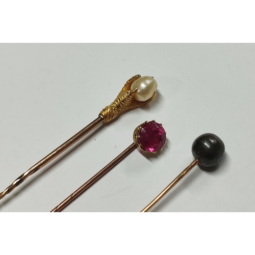 232 - Three unmarked gold metall tie-pins, one a pink sapphire, one a claw surrounding mother of pearl and... 