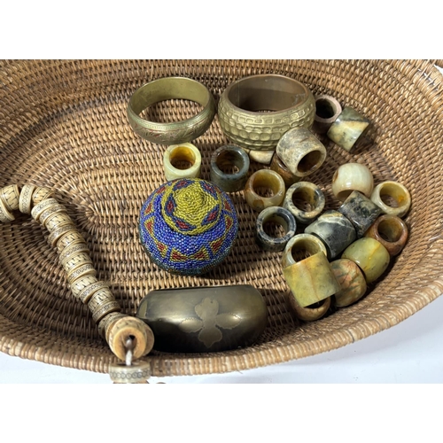 184 - Collection of Chinese natural stone rings, three brass bangles and a bone necklace with basket (Qty)