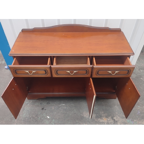 604 - A Rossmere sideboard comprising of three drawers above three doors with brass handles