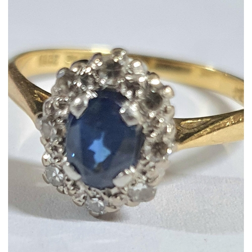 91 - Large oval cut Sapphire surrounded by smaller round cut diamonds, the yellow metal shank stamped 18C... 