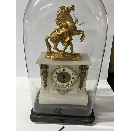 142 - Ornate French gilt mantle clock housed in huge glass dome with key