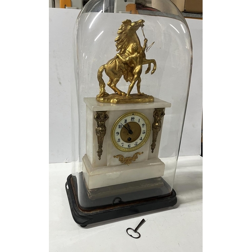 142 - Ornate French gilt mantle clock housed in huge glass dome with key