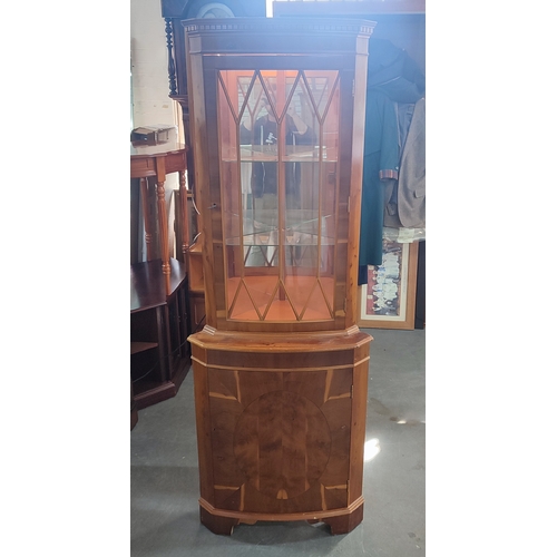 322 - A fine quality glazed burr-yew effect illuminating corner cabinet with glass inner shelves