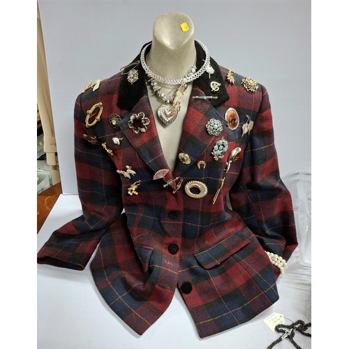 56 - Half length table top bust mannequin wearing ladies tartan jacket and displaying many brooches and a... 