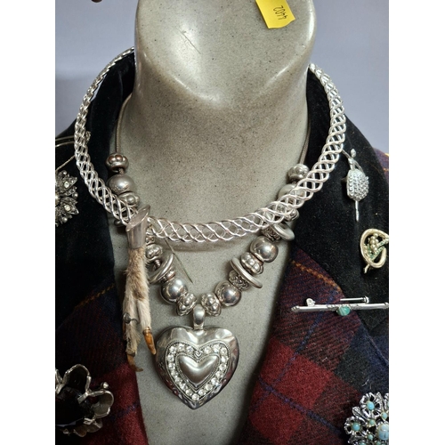 56 - Half length table top bust mannequin wearing ladies tartan jacket and displaying many brooches and a... 