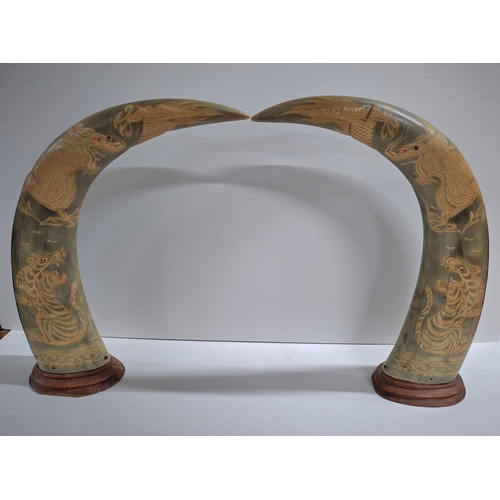 193 - Pair of animal horns on wooden stands with etched Tiger and other animal decoration (2)