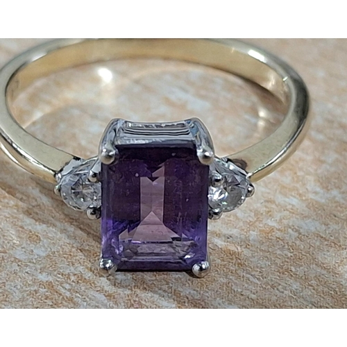 188 - 9ct yellow gold ring with a large emerald cut Amethyst, flanked to either side by a small round cut ... 