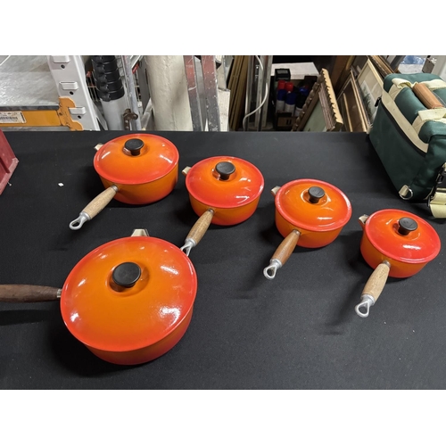 105 - Graduating sized set of five orange Le Creuset lidded sauce pans (5)