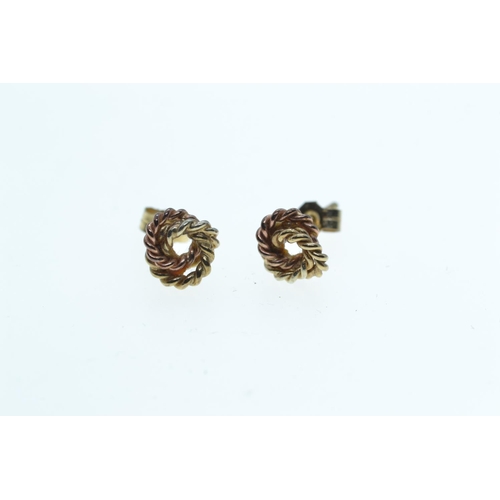 133 - Two pairs of 9ct gold ear studs, one set with topaz, the other designed as a tri-colour gold knot, g... 