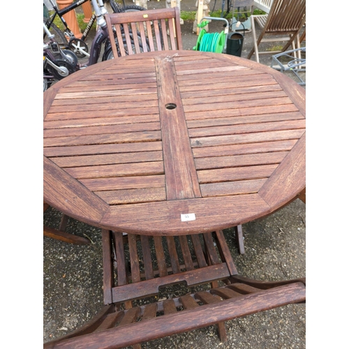 55 - Teak folding garden circular table with 4 folding chairs. Appears recently re-coated/varnished.