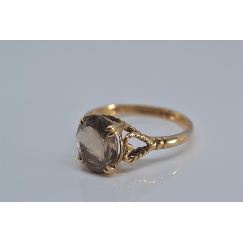 131 - 9ct gold ring claw-set with a smoky coloured stone, 9x8mm, size O/P, gross weight 2.2 grams