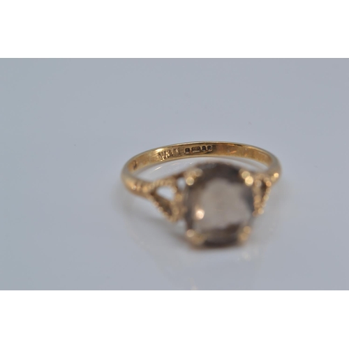 131 - 9ct gold ring claw-set with a smoky coloured stone, 9x8mm, size O/P, gross weight 2.2 grams