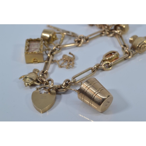 49 - 9ct gold charm bracelet with heart-shaped padlock clasp, suspending twelve 9ct gold charms, each lin... 