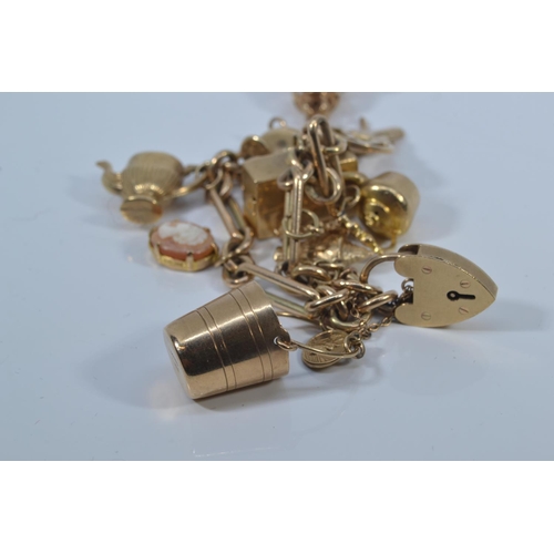 49 - 9ct gold charm bracelet with heart-shaped padlock clasp, suspending twelve 9ct gold charms, each lin... 