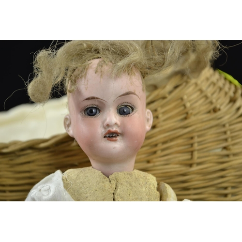 401 - Antique baby doll, head marked '390 A10/OM Made in Germany', length 23 cms, in wicker cradle