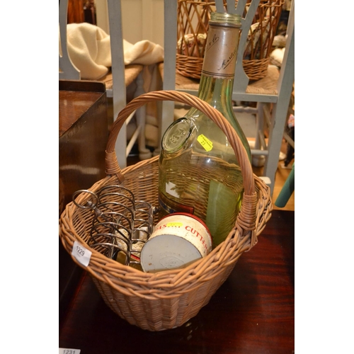 1229 - Wicker basket with contents. Including, very large empty Martell brandy bottle, plated toast rack, 