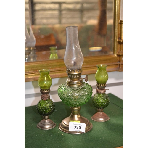 339 - Three small green glass oil lamps, tallest 25cm, smallest 13cm