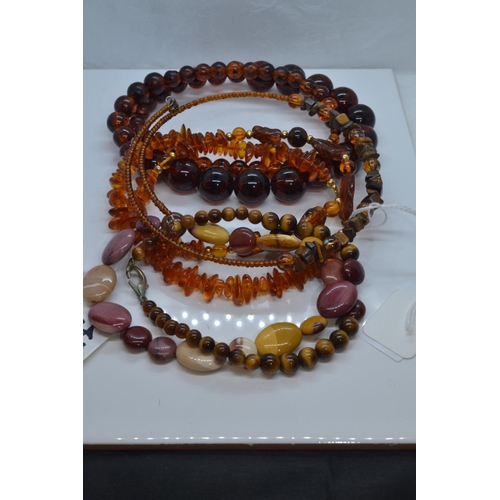 445 - Four necklaces, including hardstone, tigers eye & amber style.