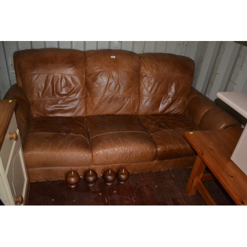 143 - Brown leather 3 seat sofa with bun feet. L195cm 