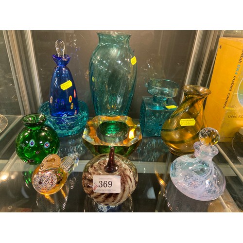 369 - Shelf of coloured glassware, including a Sowerby slag glass cup, Caithness style vase with stopper, ... 