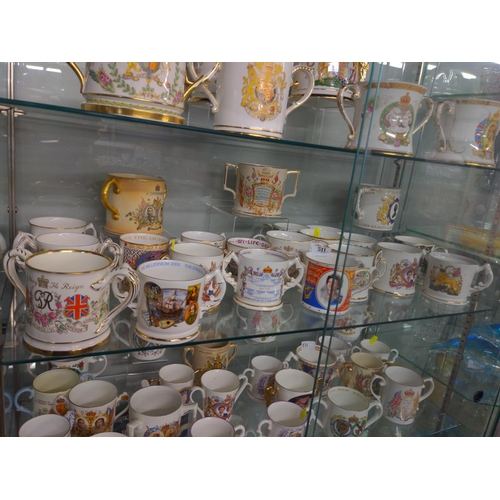 511 - Two shelves of Commemorative Loving Cups inc, Devon Ware, Royal Stafford, Aynsley and Royal Crown De... 