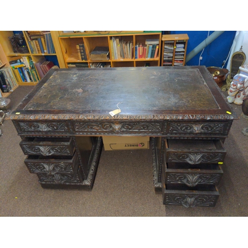 603 - Oak pedestal desk with leather inset on original wood & brass castors, drawers heavily carved wi... 