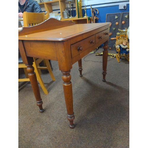 445 - Small two drawer bedroom table in mixed woods with back gallery.