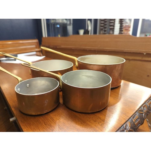 665A - Four graduated copper pans with brass handles, largest diameter 16.5cm